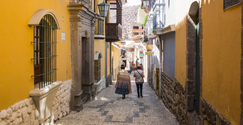 Bolivia, La Paz, gamlebyen. Kvinne i tradisjonelle klær går langs gaten. Foto