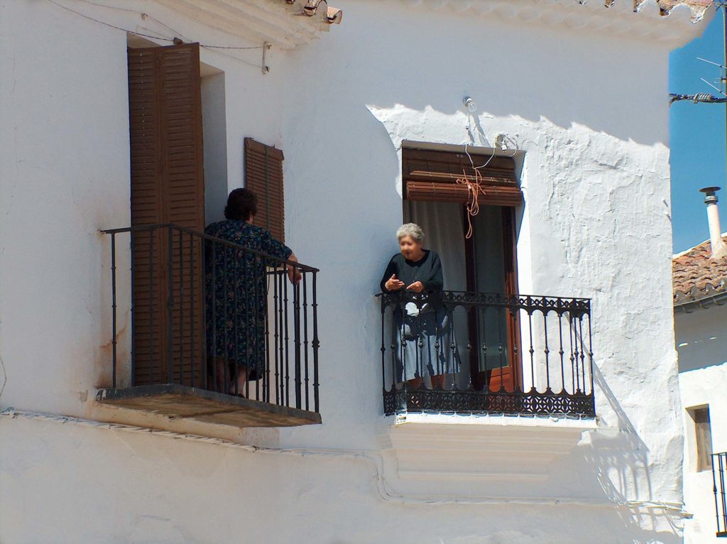 To eldre damer står på hver sin balkong og snakker sammen. La Mancha, Spania. Foto
