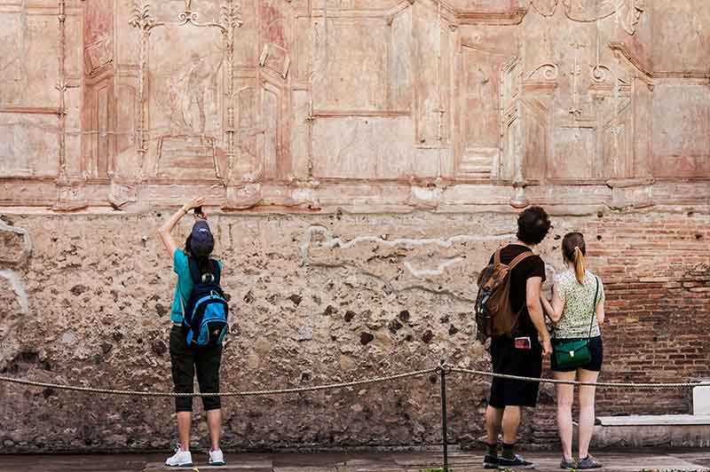 Italia, Pompeii. Turister som tar bilder av fresker.